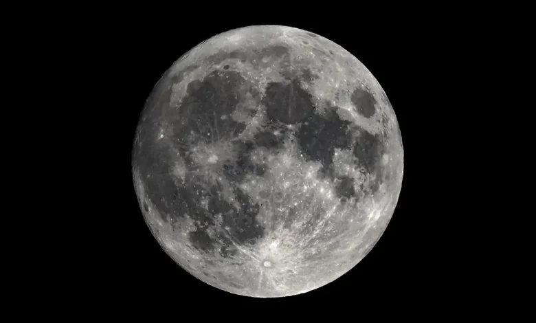 La Lune en pleine phase, vue avec un télescope astronomique, révélant les détails de sa surface avec des cratères et des nuances claires et sombres.