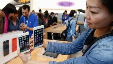 Une femme montre l'iPhone 6 et 6 Plus à des photographes, dans un Apple Store de Tokyo.