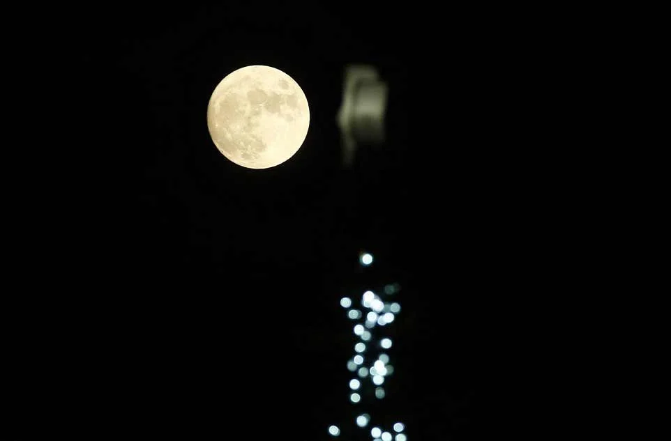 La pleine Lune se lève au-dessus d'un arbre de Noël décoré à Trafalgar Square, le soir de Noël