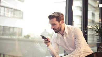 Un homme qui regarde son téléphone portable à côté d'une fenêtre