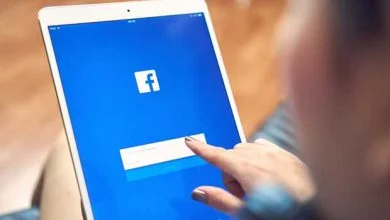 Une fille appuie sur l'écran d'un ordinateur en se connectant sur Facebook