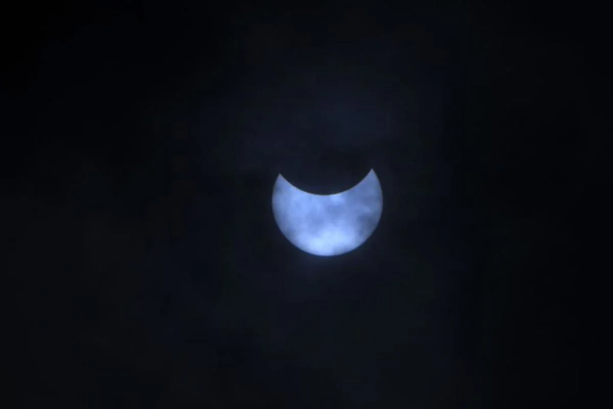 La lune se déplace devant le soleil pendant l'éclipse solaire annulaire, vue à travers les nuages depuis Katmandou.