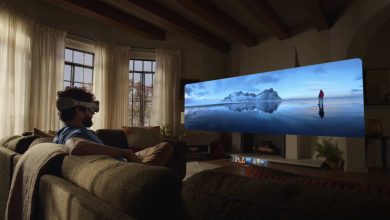Un homme portant un casque Apple Vision Pro assis sur un canapé, regardant une projection immersive d'un paysage de montagne glacée.
