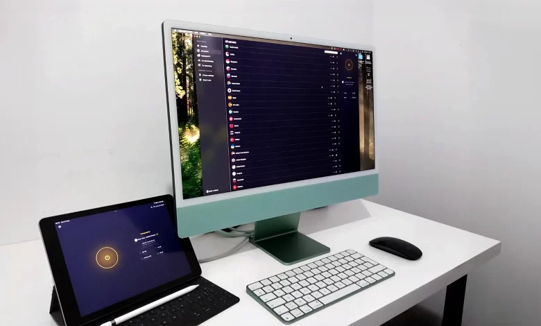 Écran d'un iMac affichant l'application CyberGhost VPN, avec un iPad Pro connecté au VPN, sur un bureau minimaliste.