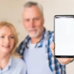 Un couple de plus de 40 ans montre un smartphone, mettant en lumière les usages du téléphone à un âge où la santé visuelle et mentale devient une priorité.