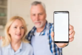 Un couple de plus de 40 ans montre un smartphone, mettant en lumière les usages du téléphone à un âge où la santé visuelle et mentale devient une priorité.