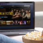 Personne mangeant du popcorn devant un ordinateur portable affichant un film en streaming. Plateforme de streaming légal pour regarder des films en ligne.