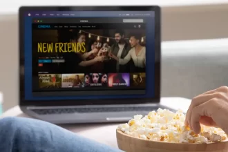 Personne mangeant du popcorn devant un ordinateur portable affichant un film en streaming. Plateforme de streaming légal pour regarder des films en ligne.