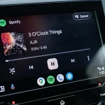 Écran d’une voiture affichant l’interface Android Auto avec Spotify en lecture, mettant en avant une navigation simplifiée et un lecteur multimédia optimisé.