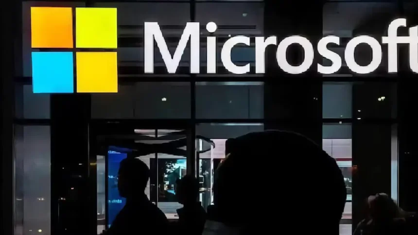 Logo de Microsoft sur une façade vitrée, avec des silhouettes de personnes au premier plan.