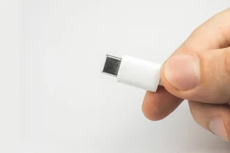 Un homme tenant un câble USB-C blanc, illustrant le concept d'un chargeur universel standardisé.