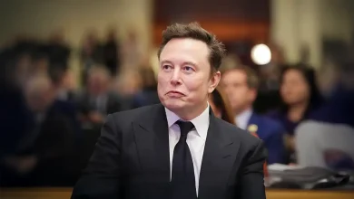 Portrait d'Elon Musk lors d'une conférence de presse, regard concentré vers la droite, en costume-cravate sombre.