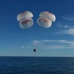 La capsule Crew Dragon de SpaceX, suspendue à quatre parachutes, amorce son amerrissage dans l'océan Atlantique après une mission prolongée sur l’ISS.